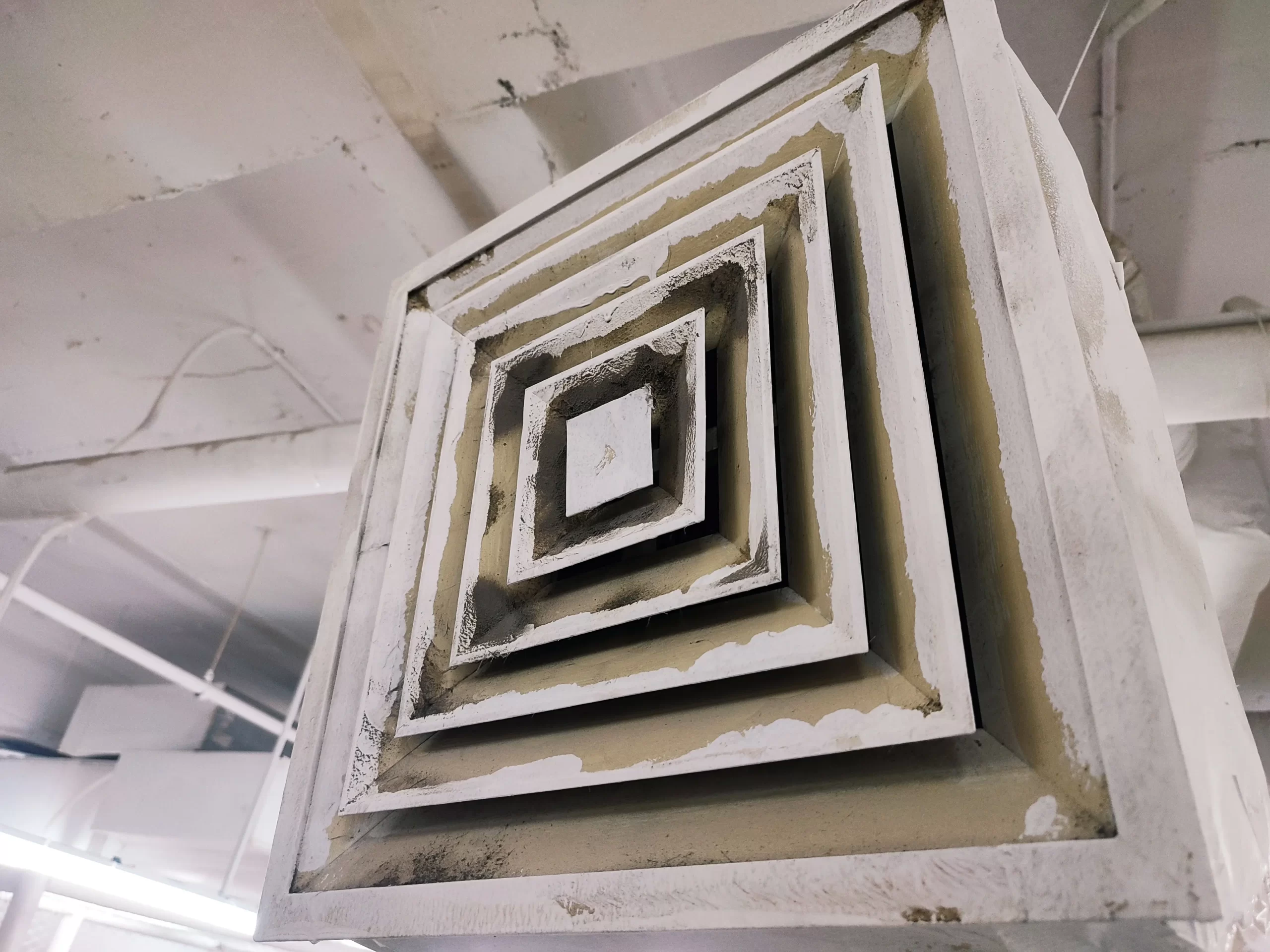 A dusty ceiling air vent grille with significant pet dander buildup